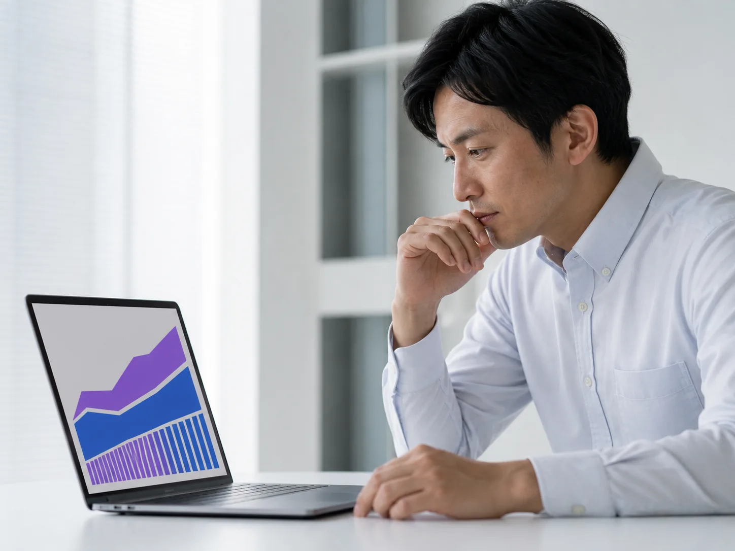 ノートPCに表示した推移グラフを見ながら、広告の進め方を検討しているビジネスパーソン